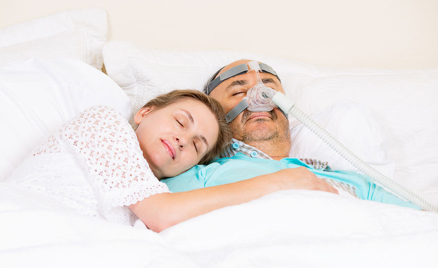 man with c-pap device sleeping peacefull with wife